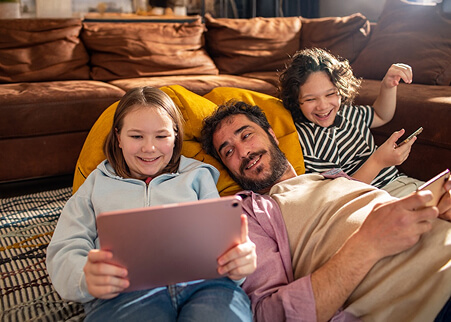 Family relaxing on the couch while using a tablet and smart phones